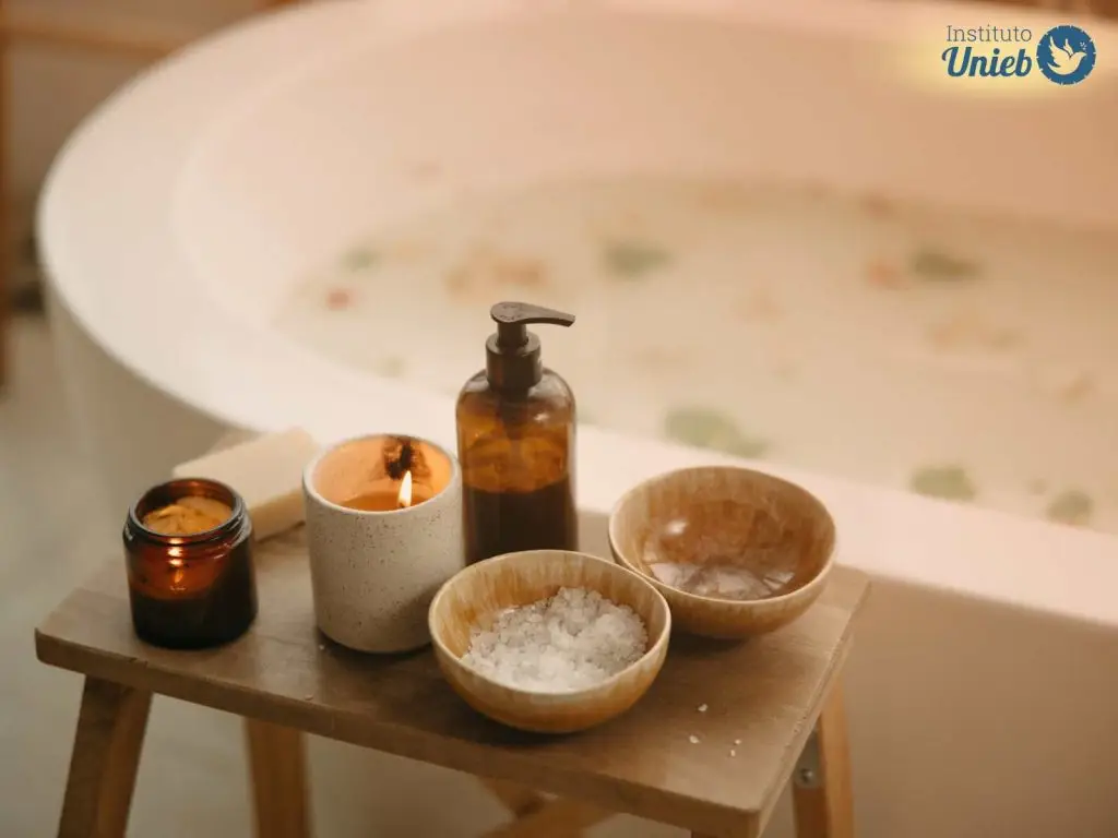 Banheira com água e ervas com mesinha de madeira ao lado com velas acesas, frasco de sabonete líquido e potes com sal grosso - Instituto Unieb (Pai de santo Roberson Dariel) - Contato 11 96982-1121 - CEP 14801-040 - Av. Dom Pedro II 562, Centro, Araraquara, SP