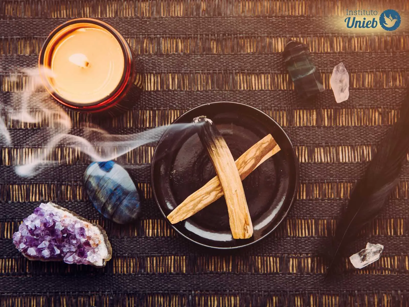 Elementos ritualísticos como vela acessa, tigela com um defumador queimando, pedras e cristais energéticos, sob uma mesa - Instituto Unieb (Pai de santo Roberson Dariel) - Contato 11 96982-1121 - CEP 14801-040 - Av. Dom Pedro II 562, Centro, Araraquara, SP