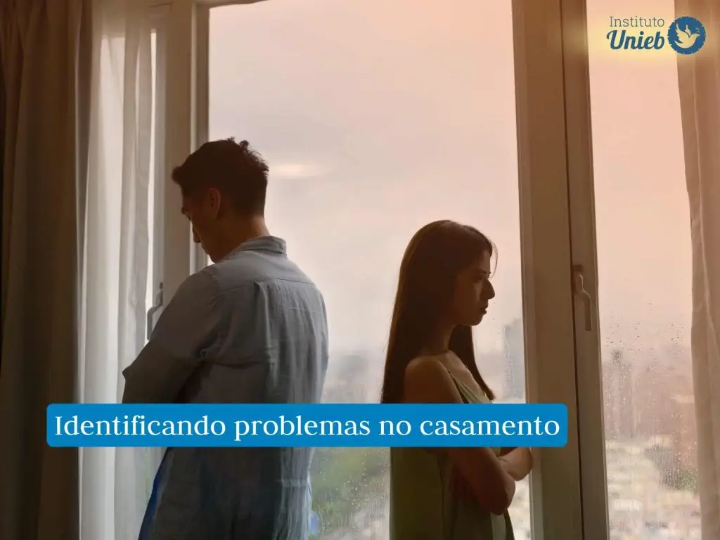 Homem e mulher virados de costas um para o outro próximo a uma janela