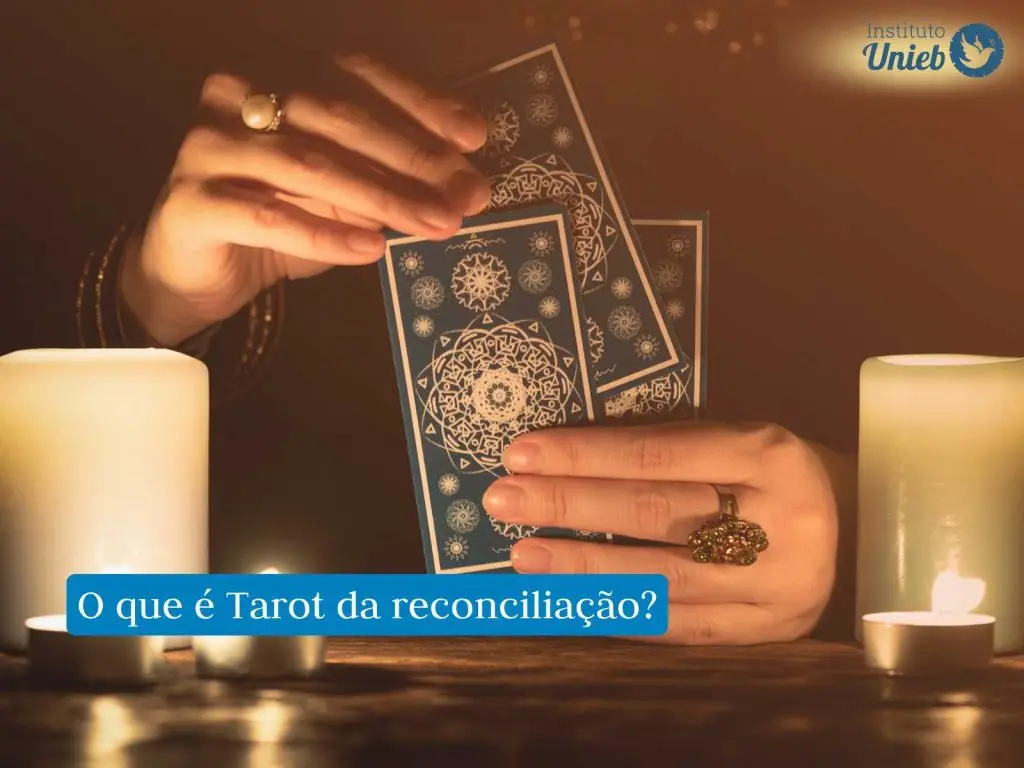 Mãos femininas segurando cartas de Tarot próximo a uma mesa de madeira onde há velas acesas