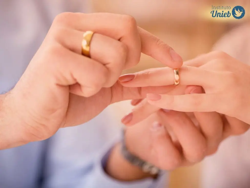 Mãos masculinas com aliança no dedo colocando uma aliança no dedo de uma mulher