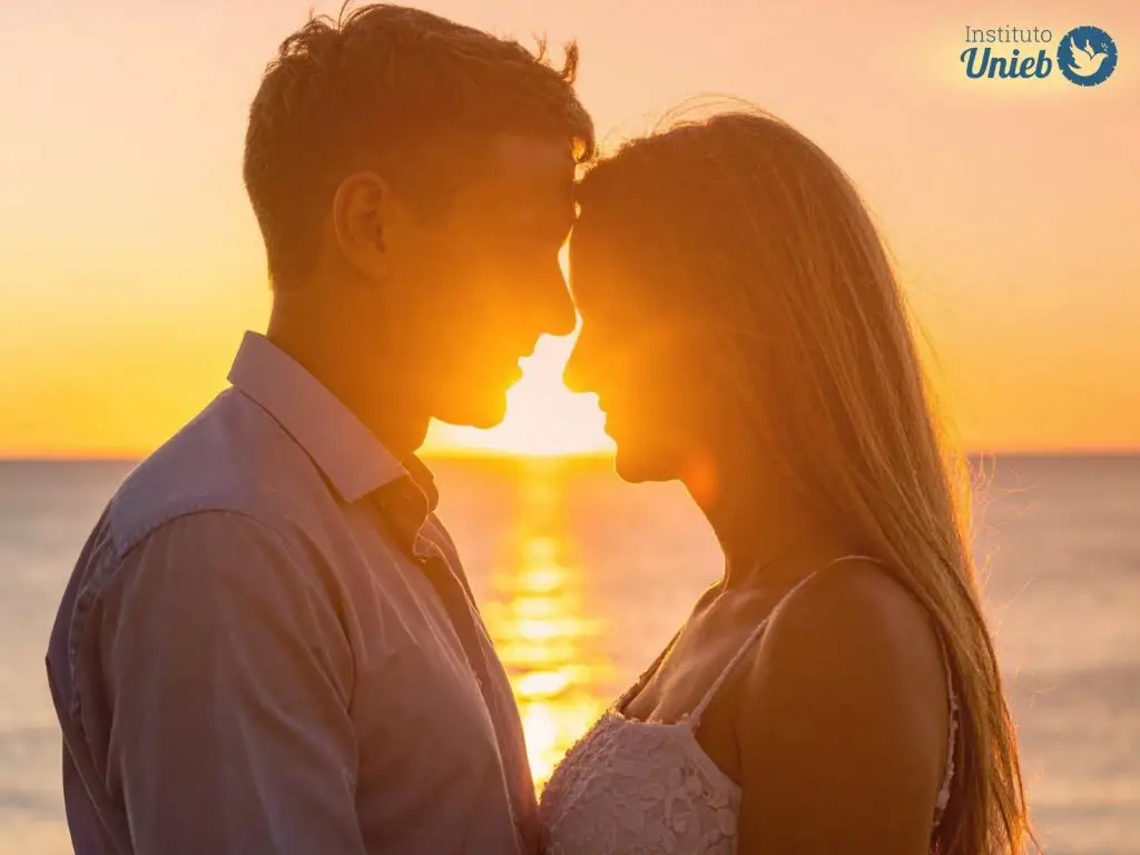Homem e mulher de frente um para o outro encostando a cabeça um no outro em uma praia com pôr do sol ao fundo - Instituto Unieb (Pai de santo Roberson Dariel) - Contato 11 96982-1121 - CEP 14801-040 - Av. Dom Pedro II 562, Centro, Araraquara, SP