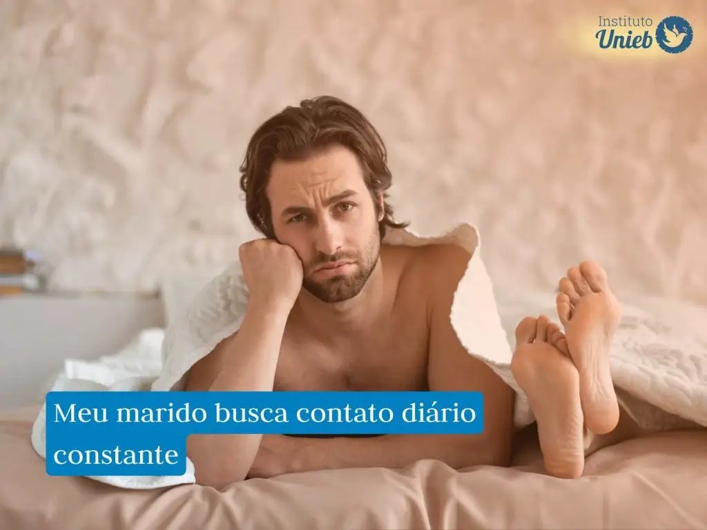 Homem embaixo da coberta deitado na cama com braço apoiado na cabeça e pés da parceira ao lado fora do cobertor