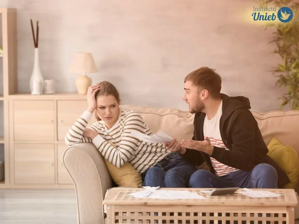 Homem e mulher sentados em sofá da sala em meio a uma discussão