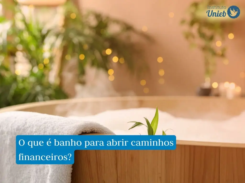 Banheira de madeira em tom claro com espuma branca, folhas verdes e uma toalha apoiada na borda