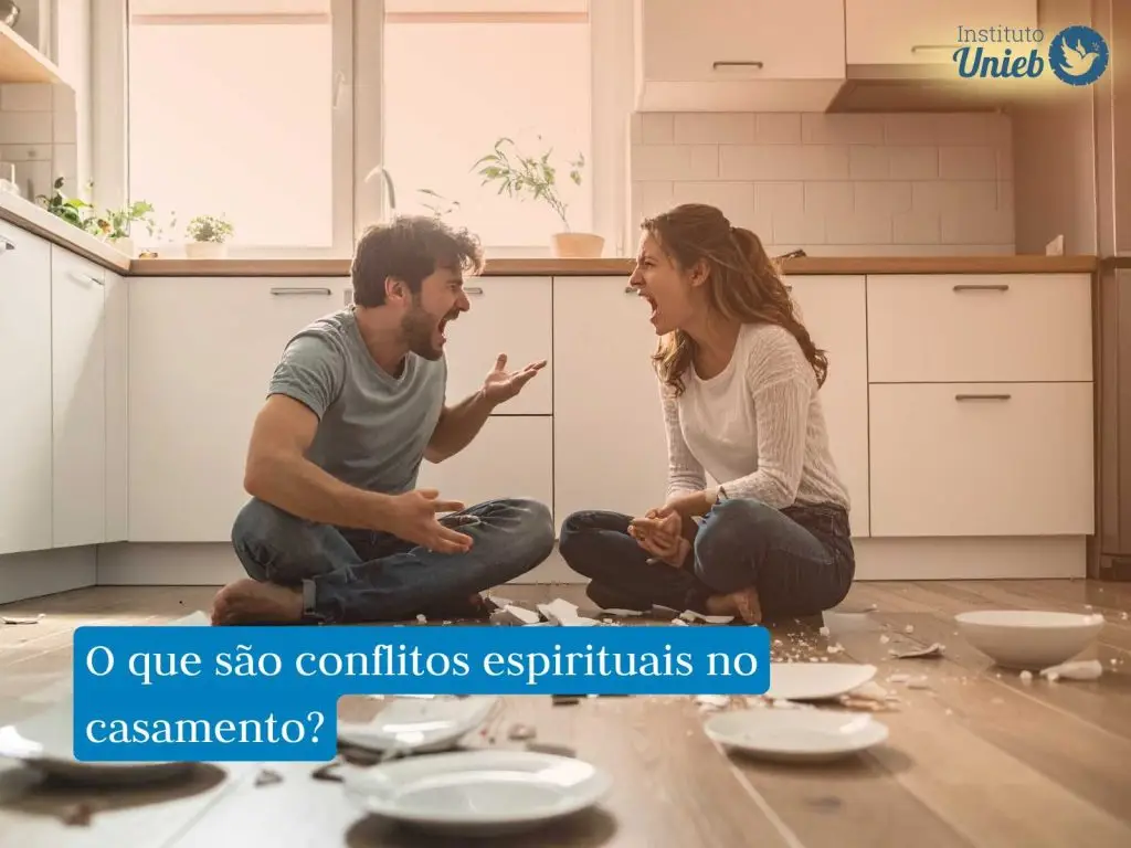 Homem e mulher sentados no chão com pernas cruzadas no meio da cozinha com pratos quebrados no chão em meio a uma discussão