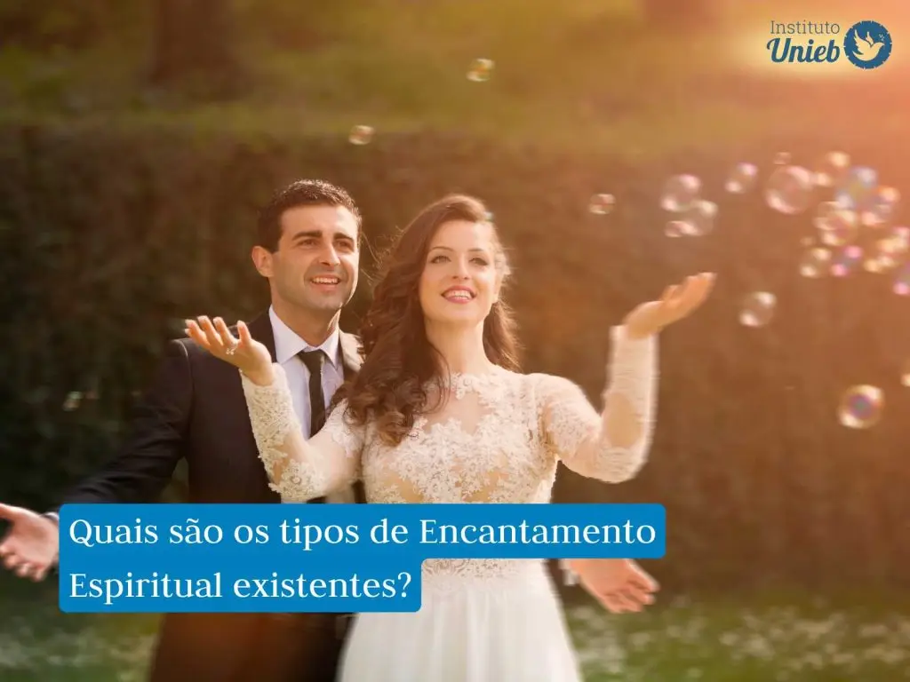 Homem vestido de terno preto e mulher com vestido de noiva em um ambiente aberto sorrindo com bolas de sabão no ar