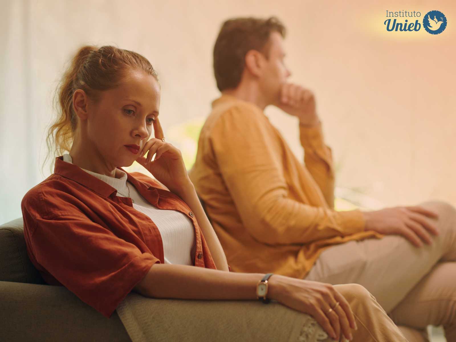 Homem e mulher sentados no sofá pensativos