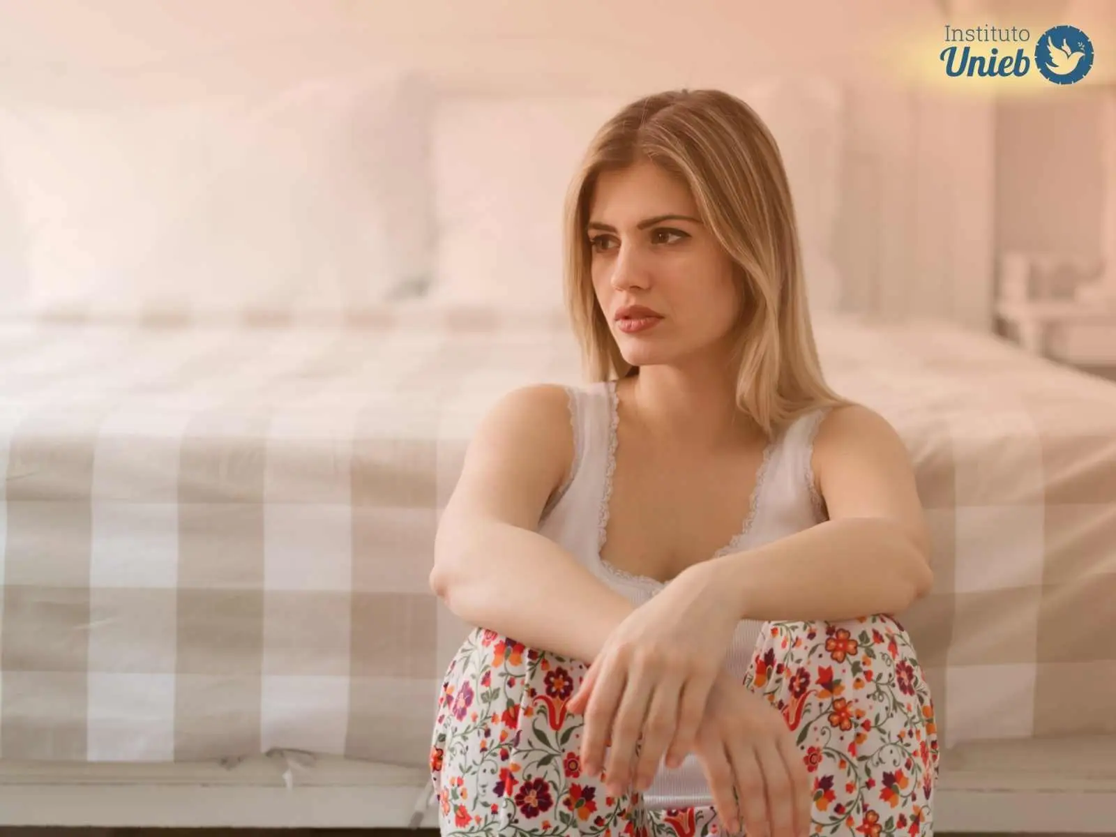 Mulher sentada no chão pensativa ilustrando uma frustração amorosa, um coração partido por uma desilusão no amor