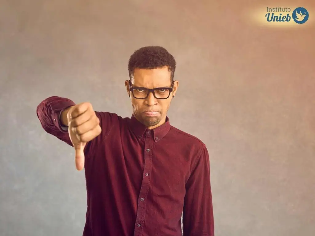 Homem fazendo sinal de negativo com o polegar virado para baixo, representando um parceiro ou marido negativo