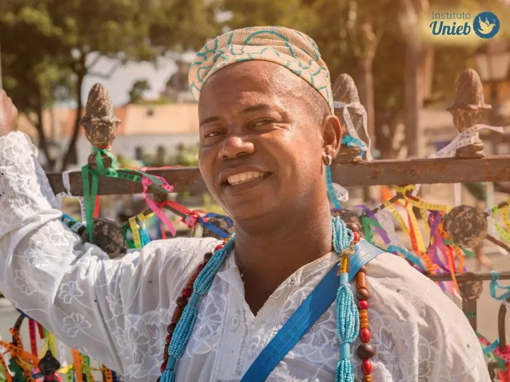 Homem vestindo roupas características de religiões como Umbanda e Candomblé, representando um líder religioso e seus significados espirituais