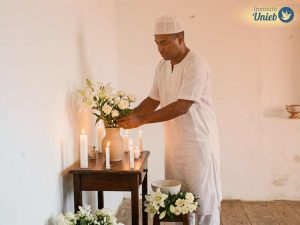 Pai de Santo ajeitando flores e velas em espaço religioso representando o sonho daqueles que sonham com Pai de Santo