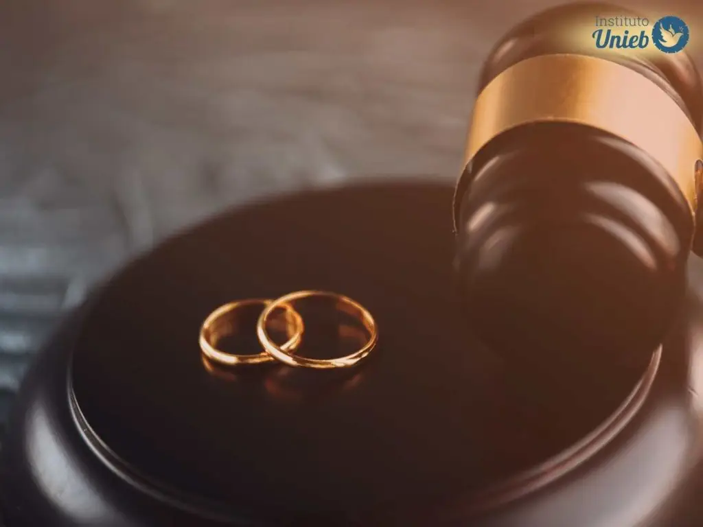 Alianças e martelo de juiz simbolizando o divórcio entre um casal