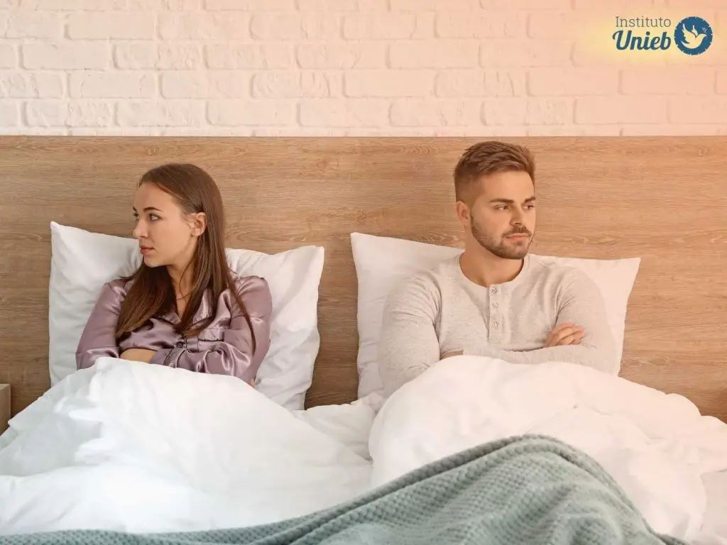 Casal sentado na cama em situação de briga simbolizando a crise dos 7 anos no casamento