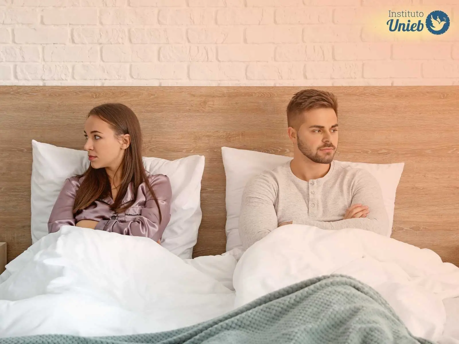 Casal sentado na cama em situação de briga simbolizando a crise dos 7 anos no casamento