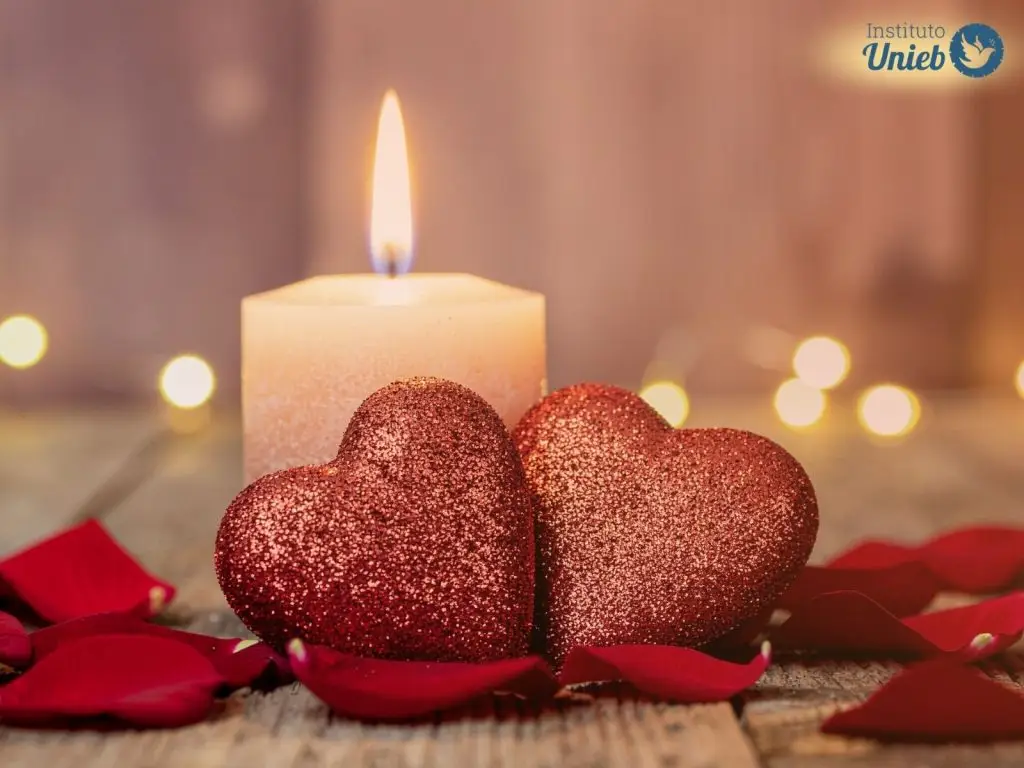 Vela acesa e corações vermelhos simbolizando a energia de rituais como Adoçamento e Amarração Amorosa
