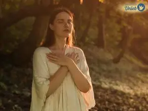 Mulher com as mãos sob o colo e olhos fechados refletindo e representando a pessoa que busca saber qual é o seu Orixá