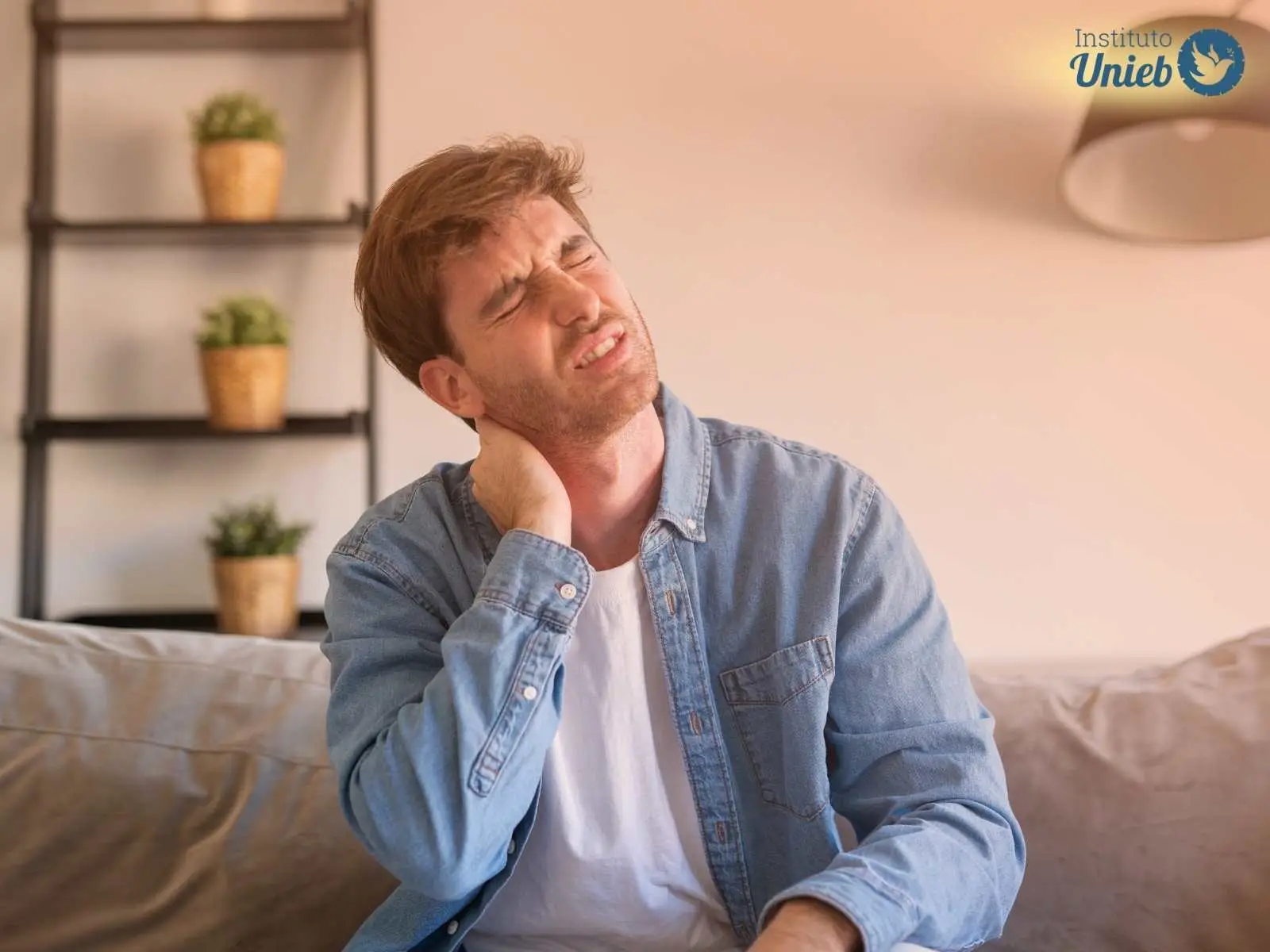 Homem sentado em sofá com as mãos no pescoço indicando uma pessoa que sente um peso ou dor nas costas