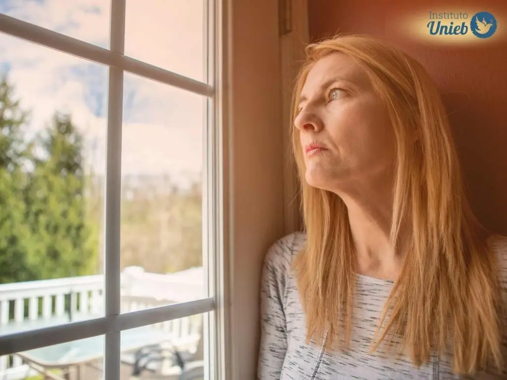 Como fazer Limpeza Espiritual no lar? Mulher olhando pela janela refletindo sobre sua casa com energia pesada e representando alguém que questiona sobre como fazer Limpeza Espiritual no lar