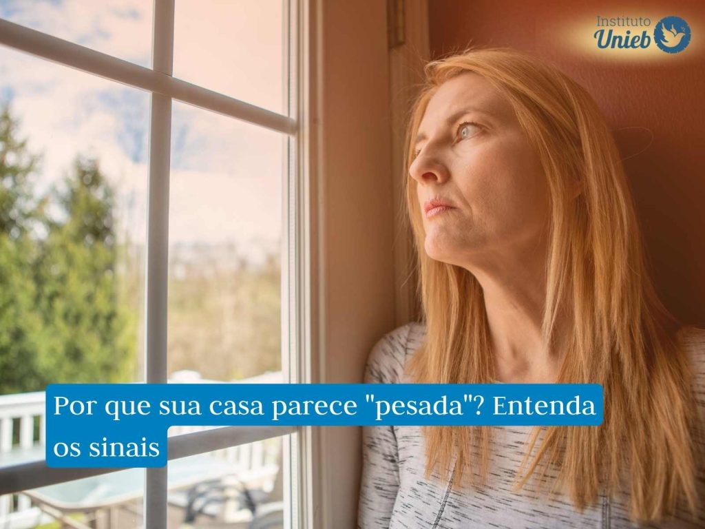 Mulher olhando pela janela refletindo sobre sua casa com energia pesada e representando alguém que questiona sobre como fazer Limpeza Espiritual no lar